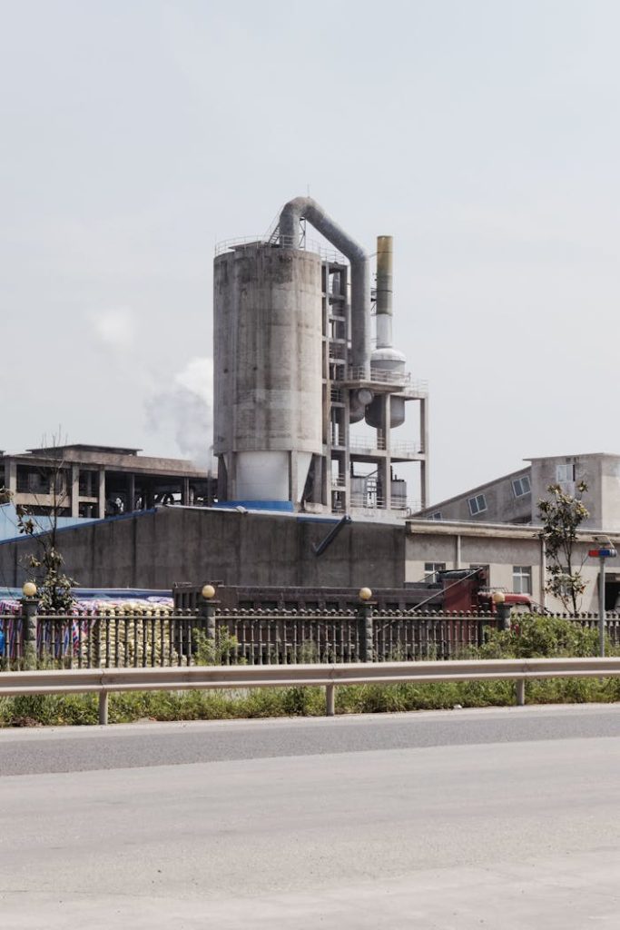 Industrial factory exterior with smokestacks emitting fumes on a clear day.