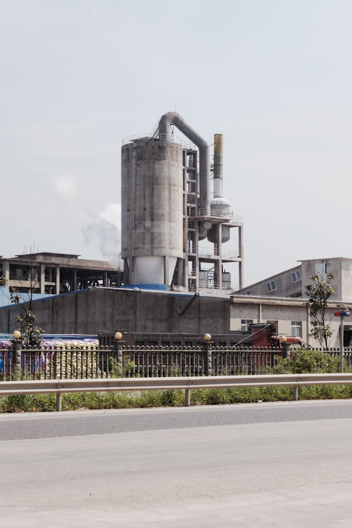 Industrial factory exterior with smokestacks emitting fumes on a clear day.