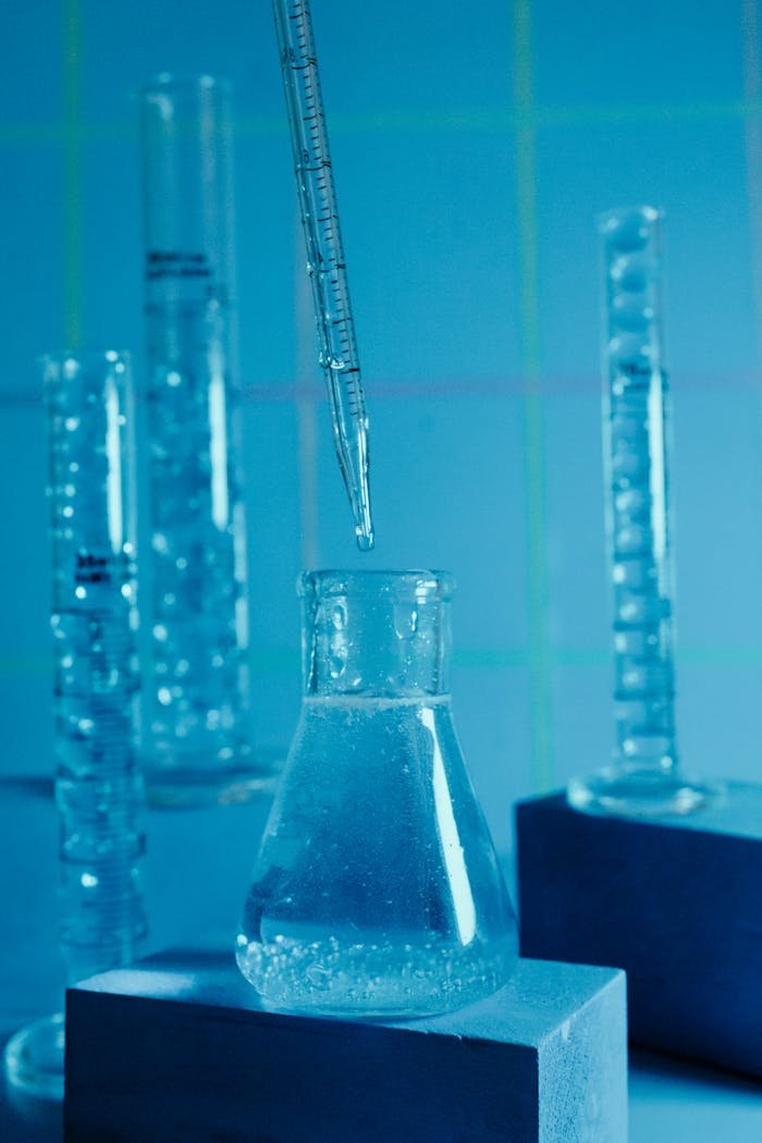 our-journey-03 Close-up of laboratory beakers with a pipette, highlighting scientific research.